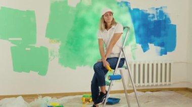 Tired Painter Worker After Painting the Wall. Exhausted Woman Taking Break From Painting Wall at Her New Home. Concept of Overworked. Hard Working and Maintenance Service