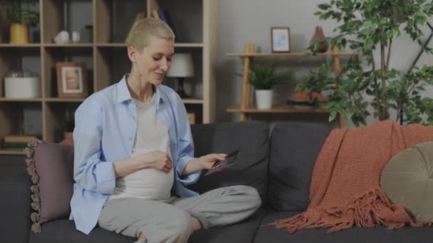 Atrakcyjna Kobieta Ciąży Siedzi Przytulnej Kanapie Patrząc Usg Lub Usg — Wideo stockowe