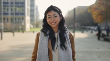 Portrait of the Attractive Smiled Asian Young Student Standing Near Student Campus. People Face. Cute Girl Looking at the Camera on the City Background. Happy Young Woman Enjoys Life