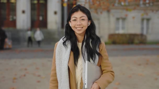 ラップトップを携帯する大学キャンパスの近くに立つ幸せなアジアの学生の肖像画 笑顔の先生 彼女のコンピュータと大学の近く 仕事の後の美しいビジネスウーマン — ストック動画