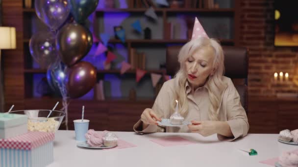 Sad Elderly Lady Celebrates Holiday Alone Blowing Out Candle Cake — Stok video