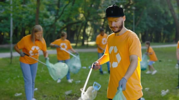 不同的生态志愿者在T恤回收符号捡拾塑料垃圾清理公园 环保人士拯救环境 生态概念 循环再用 — 图库视频影像