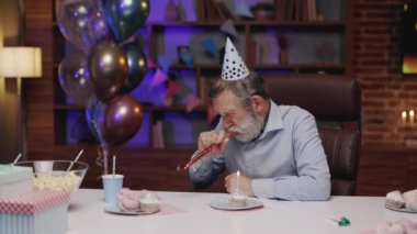 Parti Şapkalı Depresyondaki Olgun Adam Evdeki Masa 'da Oturuyor ve Yanan Mum' la Çörek 'e Bakıyor, Doğum gününde Mutsuz Hissediyor. Yalnızlık İnsanlar Kavramı