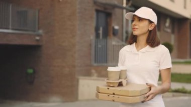Yemek teslimatı. Mavi Renkli Üniformalı Kadın Kurye Pizza Kutuları ile Residential Area yakınlarında yürüyor, Siparişi veriyor. Postacı ve Ekspres Bakkal Servisi Konsepti