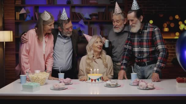 在疗养院举行的生日聚会 老年组 老金发女人吹蛋糕棒 向生日的朋友问候 高级妇女生日聚会 — 图库视频影像