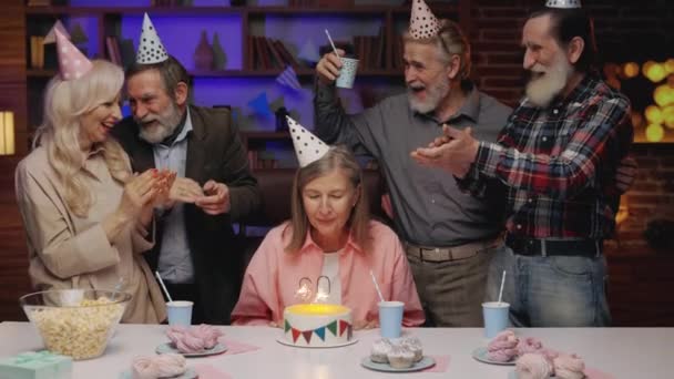生日老年人派对 60周年纪念日 成年人士小组在家中用蛋糕和烛光庆祝老年妇女诞辰 老朋友在饭桌前拍手 — 图库视频影像