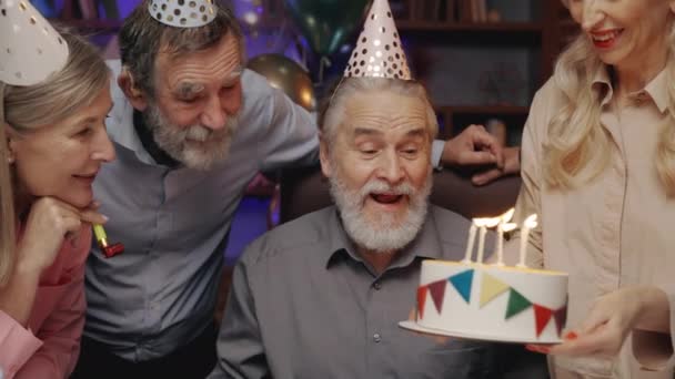 Älterer Mann Mit Geburtstagsmütze Bläst Kerze Auf Geburtstagstorte Aus Und — Stockvideo