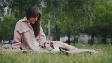 Mutlu Kafkas Kadın Hayvan Sahibi Jack Russell Puppy 'i okşuyor Çimenlikteki Battaniyede Oturan Köpeğe Sevgi Gösteriyor. Halk ve Köpek Arkadaşlığı Konsepti