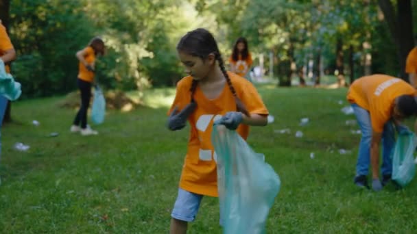 环保小女孩义工在本袋中收集塑料垃圾 环抱符号清洁公园的T恤环保人士团体 安全生态概念 — 图库视频影像