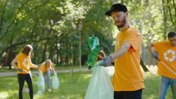 白胡子人生态义工在收集垃圾袋中的塑料时 使用垃圾捡拾器 环抱符号清洁公园的T恤环保人士团体 安全生态概念 — 图库视频影像