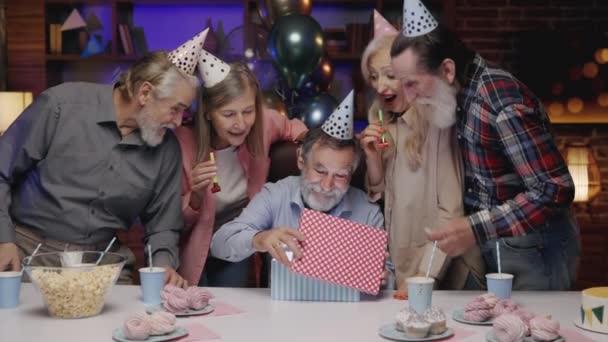 Uśmiechnięty Starszy Dziadek Nosi Świąteczny Kapelusz Urodzinowy Otwiera Pudełko Prezentów — Wideo stockowe