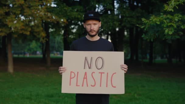 高加索人生态活跃分子举行没有塑料海报展示一个标志抗议污染的森林 男志愿者看着摄像机 生态学 公众示威 — 图库视频影像
