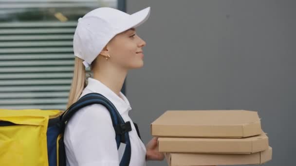 笑顔白人宅配便の女性のサイドビュー黄色のバックパックを運ぶ ピザお客様に歩く ファーストフード配達郵便配達とエクスプレス食料品配達サービスの概念 — ストック動画