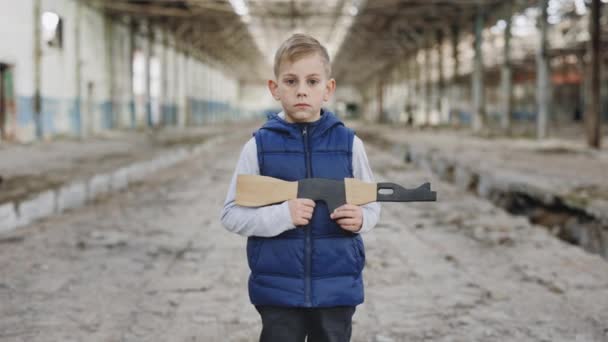 Retrato Del Niño Sostiene Una Pistola Juguete Sobre Fondo Planta — Vídeo de stock