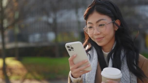 Asiatisk Flicka Utanför Med Hjälp Sin Smartphone Och Svepa Håller — Stockvideo