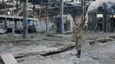 Asker üniformalı bir çocuk. Yok Edilmiş Gezegen 'de El Yürüyüşünde Beyaz Duman Bombası tutuyor. Tehlike uyarısı, çocuk yardım istiyor. - Savaş. Harabeler