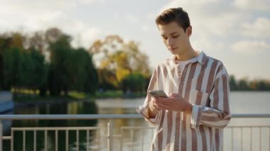 Sokakta yürüyen genç adam akıllı telefonunu kullanıyor, arkadaşlarıyla mesajlaşıyor. Dışarıdaki beyaz erkek, yürürken hareket halinde. Genç Kullanıcı Sohbeti İnternette. İletişim