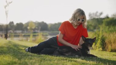 Kafkas Tarzı Kadın Parkta Çimlerde Uzanıyor Mini Boğa Teriyerine Sevgisini Gösteriyor. Kadın, evcil hayvan arkadaşıyla oynuyor. Halk ve Köpekler Dostluk Konsepti