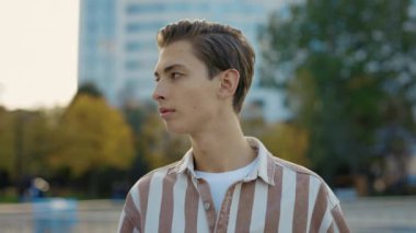 Beyaz, güzel bir adam caddenin dışında duruyor ve kameraya bakıyor. Günlük giysiler giyen adamın portresi. Keyifli Genç Erkek 'in Belden Yukarı Portresi Sokakta Duruyor ve Gülümsüyor