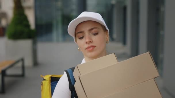 白人女性宅配便でホワイト制服 運ぶイエローバックパック 保持重いパッケージそれらを運ぶビジネスセンター クライアントに大きな紙箱を届ける若い郵便配達人 — ストック動画