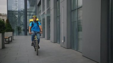 Müşteri ve Müşterilere Sipariş Vermek İçin Bisiklete Binen Afrikalı Amerikalı Erkek Kurye. Özel üniformalı, sırt çantası ve kask taşıyan çok ırklı Postacı. Teslimat Konsepti