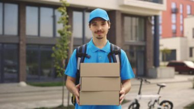 Positif Kafkas Postacısı 'nın Dışarda Karton Kutuları Tutarken Portresi. Erkek Teslimatı Özel Üniformalı Kutu 'yu kameraya gösteriyor. Halk ve Meslekler. Teslimat Hizmeti