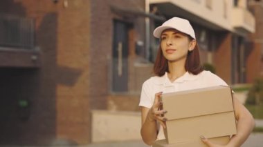 Çekici Kafkasyalı Postacı Dışarıda Karton Kutuları Tutuyor. Kutuları taşıyan özel üniformalar giyen güzel bayan teslimatçı. Halk ve Meslekler. Teslimat Hizmeti