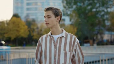 Beyaz, gülen adam caddenin dışında dikiliyor ve kameraya bakıyor. Günlük giysiler giyen adamın portresi. Keyifli Genç Erkeğin Belden Yukarı Portresi