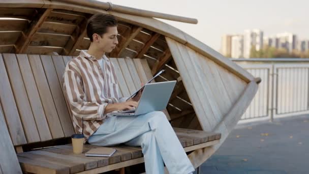 ノートパソコンやノートブックを使って商品を計算する オンラインハンサムなビジネスマン 屋外に座っている間 彼のラップトップを使用して男 オンライン教育 — ストック動画