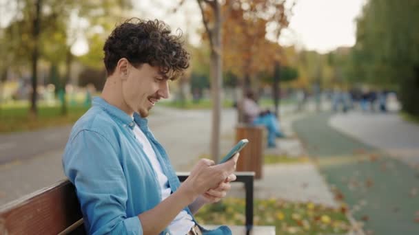 Sakallı Adam Sokakta Bankta Otururken Akıllı Telefonunu Kullanırken Arkadaşlarıyla Mesajlaşırken — Stok video