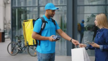 Yemek teslimatı. Afro-Amerikan Erkek Kurye paketi İş Merkezi 'ndeki beyaz kadın müşteriye veriyor. Sipariş İnternetinin Müşteri Ödemeleri. Bağlantısız NFC Terminal Ödemesi