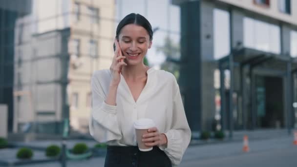 魅力的な自信白人ビジネスマン街の通りを歩き オフィスビルの近くの携帯電話で話す女性 ストリートでスマートフォンを使用して若い女性をブルネット 人とのコミュニケーション — ストック動画