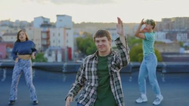 Etkileyici Çatı Dansı Şovu: Genç Bir Erkek Etkileyici Hip Hop Hareketleri ve Arkaplanda Dans Eden Arkadaşları. Çatıda Dans Hareketleri sahnelemek. Dans, Vücut, Hareketler, Eylem Konsepti