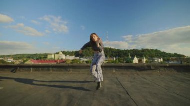 Beyaz yetenekli hip-hop 'çı kadın çatıda dans ediyor kameraya bakıyor ve dışarıda inanılmaz jestler ve hareketler yapıyor. Sanatçı performansı. Sokak dansı. Dans, hareketler, aksiyon konsepti