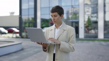 Kafkasyalı Çekici İş Kadını 'nın portresi. Laptop kullanarak dışarıda duruyor. Şirin Bayan Dışarıda Çalışan İşçi. Gülümseyen Patron evrakları kontrol ediyor. Bilgisayarı Tutan Kadın Yönetici Pozu