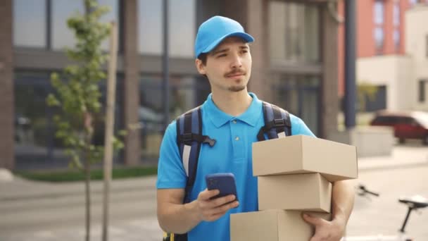 Smiling Courier Going Building Holding Paper Boxes Mobile Phone Hand — Stok Video