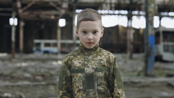 一个身穿军服 站在残破的植物中 看着相机的小男孩的画像 儿童兵 战士和战争的概念 — 图库视频影像
