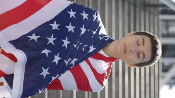 垂直录像 引以为傲的女人的画像 代表了她的国家 并在她的背上挂上了美国国旗 时尚的美国女商人穿着美国国旗作为爱国主义的标志 — 图库视频影像