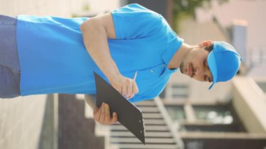 Mavi Üniformalı Değerlendirme Evi 'nde emlakçı. Yeni Kır Evi 'nde dururken Apartman hakkında notlar almak ve tasvir etmek. Emlakçı çalışıyor, verileri yazıyor. Dikey Video