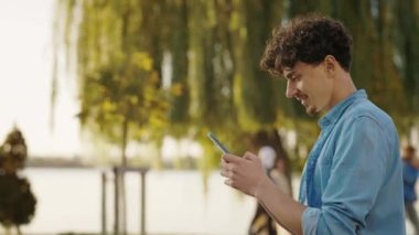Genç Kafkasyalı Gülümseyen Adam Parkta Yürürken Akıllı Telefon Sohbeti Yapıyor. Halk ve İletişim Konsepti