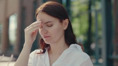 Yorgun kızıl bir kadın alnına masaj yaparken gözlüğünü çıkarıyor. Çalışmaktan yorgun düşmüş bir bayan iş gününden sonra göz yorgunluğu ve migren hissediyor. Baş ağrısı, görsel yorgunluk ve göz ağrısı konsepti