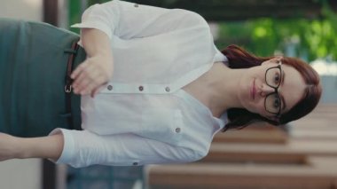 Kızıl İş kadınının resmi takım elbiseli portresi İş Merkezi 'nin yakınında kameraya bakarken el ele tutuşuyor. Halk ve İş Konsepti. Dikey Video