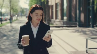 Resmi Takım Elbise Giyen Çekici Bayan Yönetici İş Merkezine Gidiyor. Cep Telefonu Kullanan, Müşterilerle Mesajlaşan, Uygulamaları Kapıp Kahve ve Çay İçin Eko Kupa Tutan Kadın