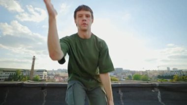 Kahverengi Saçlı Bir Genç Çatıda Hip-Hop Danslar Yapıyor, Hareketlerini ve Kamera Yeteneklerini Gösteriyor. Sanatı için neşe ve tutku saçar.