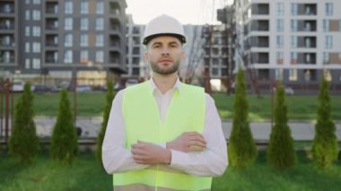 Kafkas İş Adamları Sert Şapkalı ya da Güvenlik Giyer. Binanın arka planında duran ve ellerini çapraz yapan kendinden emin genç müteahhit ya da çekici inşaatçının portresi