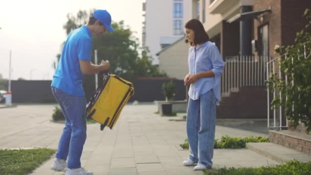 食料の配達 バックパックを運ぶと正の美しい女性に食品パッケージを取得する白人男性宅配便 ホームオーダードアへの配送 交通機関 — ストック動画