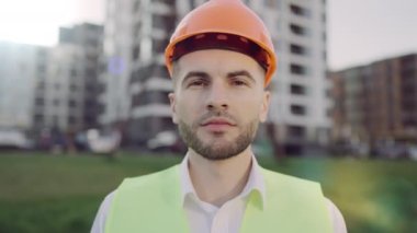 Erkek İnşaat Profesyoneli Güvenlik Üniforması: Güvenilir Ağır İşçinin Portresi. İnşaatçı, mimar, teknisyen, ustabaşı ve müfettiş binanın yakınında dikiliyor..