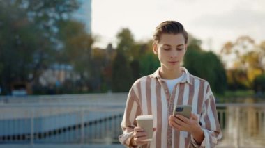 Kafkasyalı Adam Smartphone, Arkadaşlarına Mesaj Yazıyor ve Sokakta yürürken bir fincan kahvenin tadını çıkarıyor. Mobil Yaşam Tarzını Kabul Etmek, Çevrimiçi Sohbetlere Girmek ve Kullanıcı Olarak Tarama