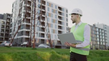 Erkek Mühendis Koruyucu Gear Denetleme Güç Hattı 'nda duruyor. Bir dizüstü bilgisayardaki elektrik sensörlerinden gelen verileri kullanarak. Enerji ve Enerji Sanayii Profesyonel İşçisi Elektrik Kulesini Denetliyor
