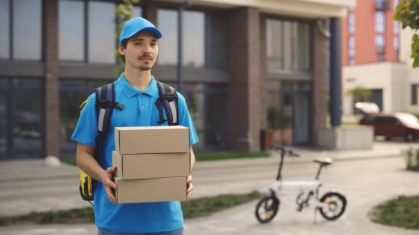 白种人邮递员拿着纸盒微笑的正面画像 身穿特殊制服的男性送货员向摄像机展示盒装 人与职业 服务交付 — 图库视频影像